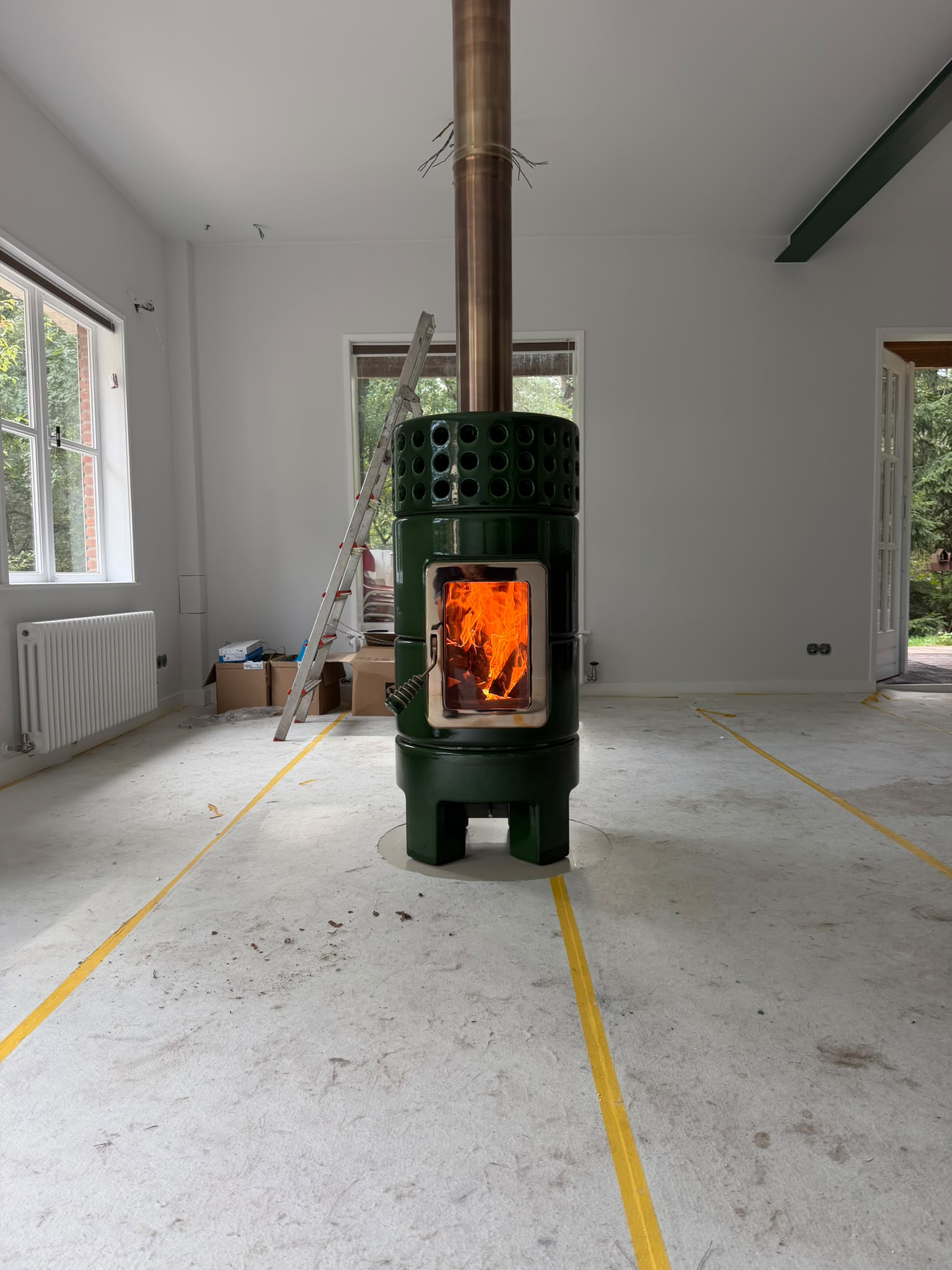 Donkergroene keramische houtkachel als middelpunt van het interieur